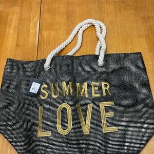 Unused Yumi beach bag w zipper, rope handles. Black metallic w gold lettering.